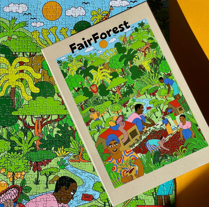 The Fairforest | 1,000 Piece Jigsaw Puzzle by Das Puzzle Kollektiv, supporting Fairventures Worldwide, shows illustrated people in a lush green forest; its colorful box rests atop the completed puzzle.