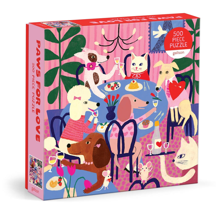 The Galison Paws For Love 500 Piece Jigsaw Puzzle features Anne Bentley's colorful illustrations of dogs and cats dining together, all in a vibrant, charming box.
