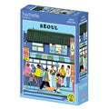 The Hachette Puzzle "Seoul" is a 1,000-piece jigsaw featuring a fagostudio street scene with people and a dog outside a building in Seoul, South Korea. Made in France.
